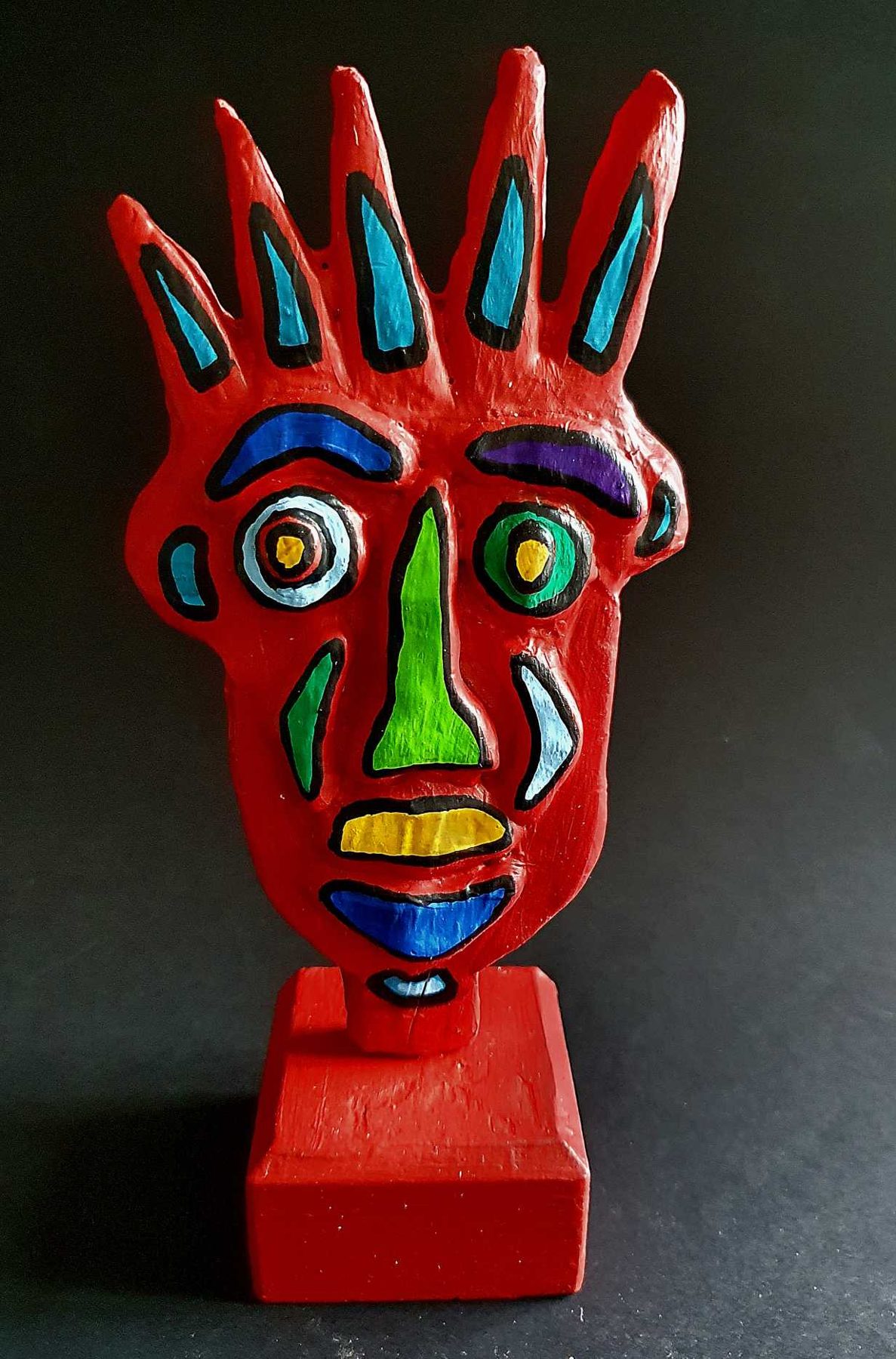 Sculpture : visage rouge aux traits cloisonnés bleu, vert et jaune